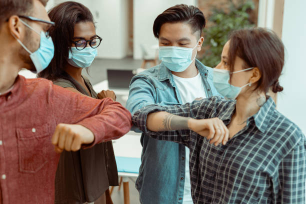 istock Students standing and greeting bumping elbows at workplace 1391972872