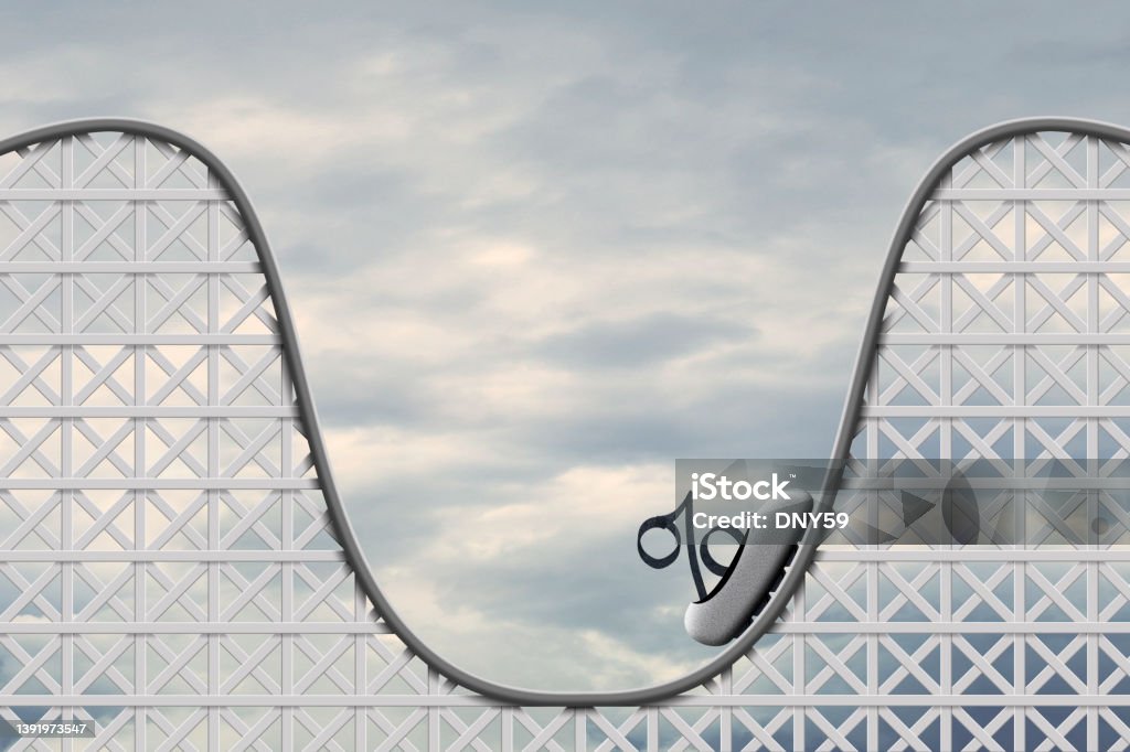 Roller Coaster of interest Rates And Inflation An interest rate symbol sits in a car on a rollercoaster as it begins to make its way back up. Interest Rate Stock Photo