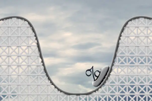 An interest rate symbol sits in a car on a rollercoaster as it begins to make its way back up.