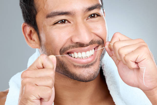istock Shot of a man using dental floss while standing against a grey background 1391974233