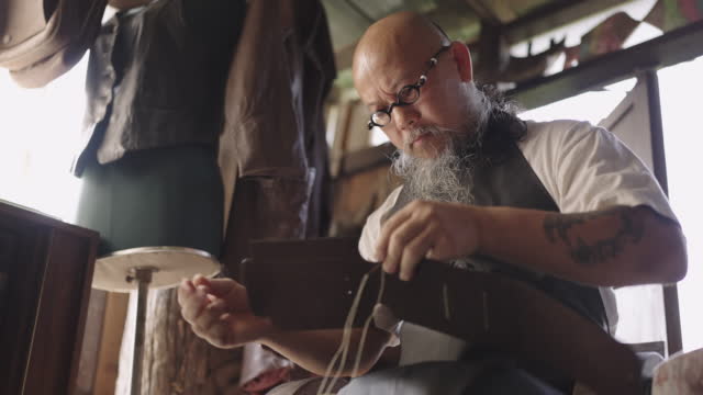 Man carefully hand sewing leather product.