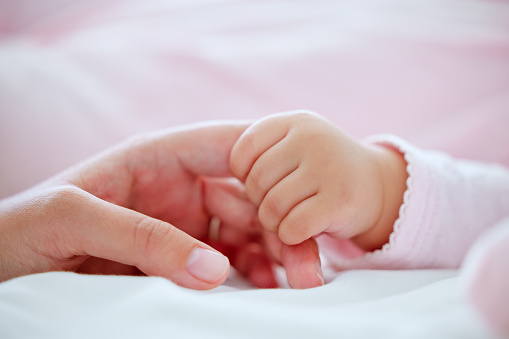 baby's hand on white fabric pattern with soft focus shooting and copy space text