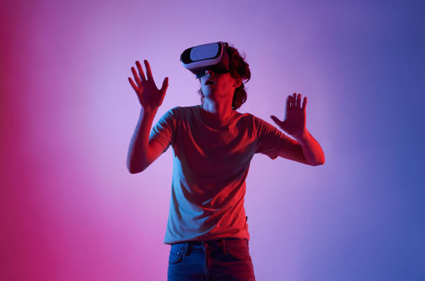 istock Amazed young man using a virtual reality headset playing video games trying to touch something with hand. 1391979468