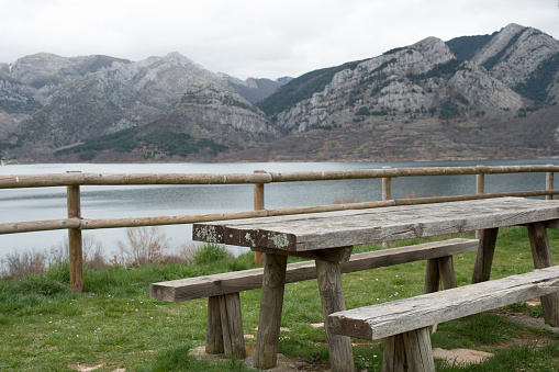 Picnic area with wooden table and bench. Magnificent view of the water reservoir at Caldas de Luna and the mountains around. Natural park of Babia and Luna
