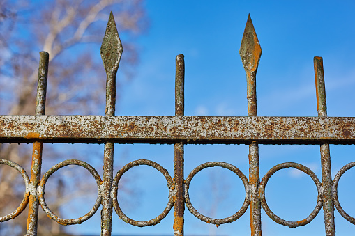 part of an old, iron, rusty fence against a blue sky.