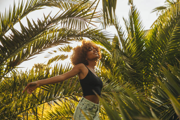 istock Pretty young afro woman among palm trees 1391992386