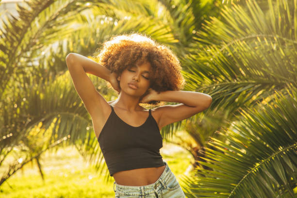 istock Pretty young afro woman among palm trees 1391992963