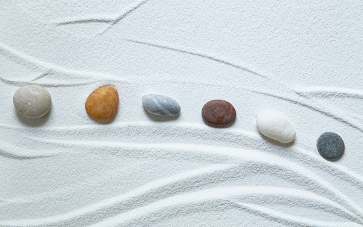 Zen garden with peble stones on white sand pattern