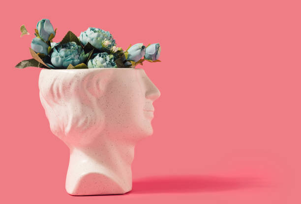 istock Marble statue head profile with spring flowers on a pastel pink background. 1391994412