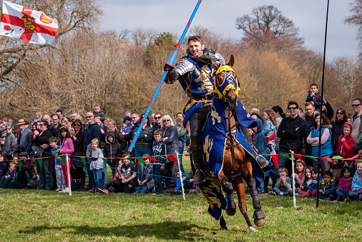 Medieval horseback jousting display and sword fighting with knights in shining  metal armour at Knebworth house, England.