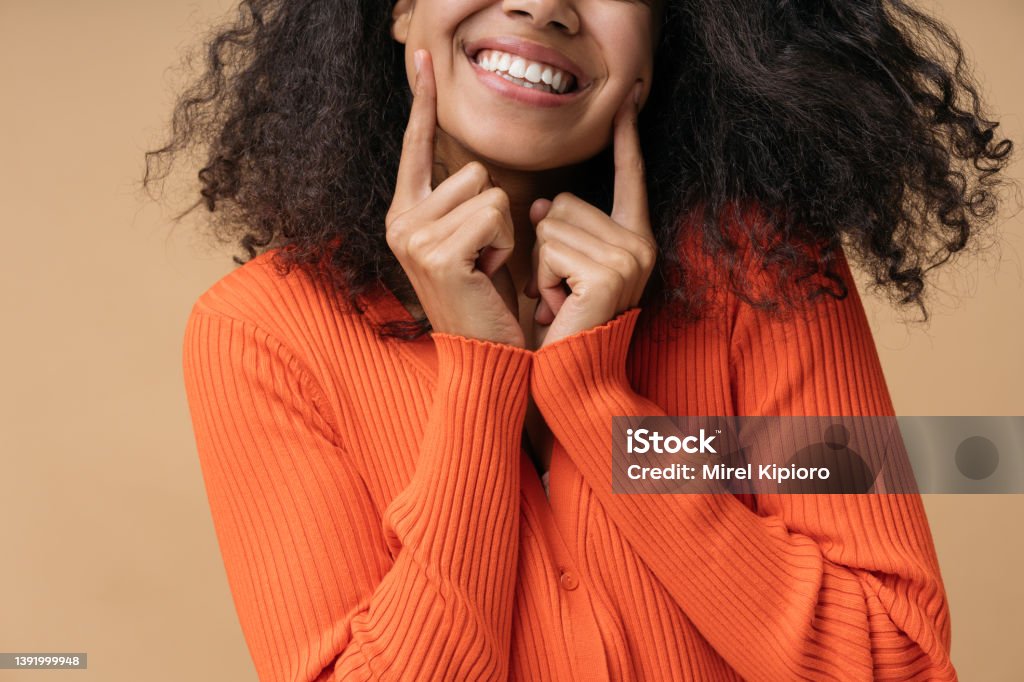 Happy African American woman pointing finger on white teeth isolated on background. Health care, dental treatment concept Close up portrait of young happy African American woman pointing finger on white teeth isolated on background. Health care, dental treatment concept Teeth Stock Photo