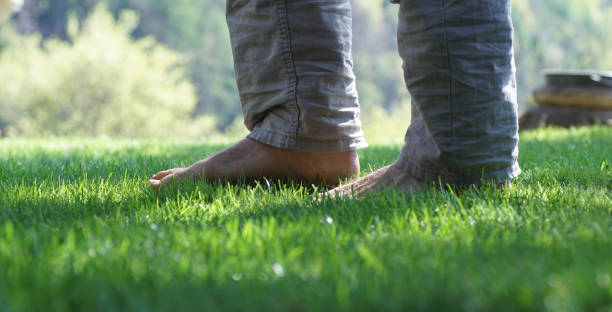 Man standing barefoot in the grass.