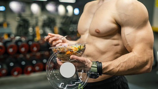 Side view of men eating healthy food in gym. Mockup your brand