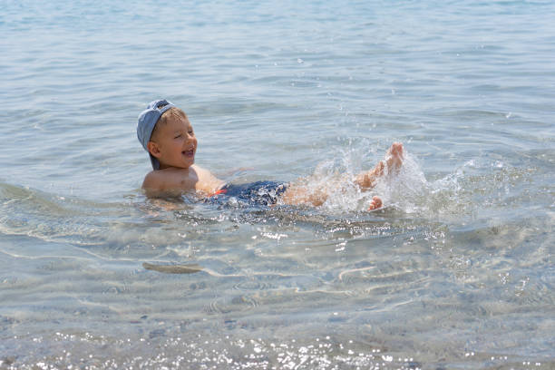 The child learns to swim. Happy child swims in the sea. Holidays in Greece The child learns to swim. Happy child swims in the sea. Holidays in Greece. Happy childhood concept family beach vacations travel stock pictures, royalty-free photos & images