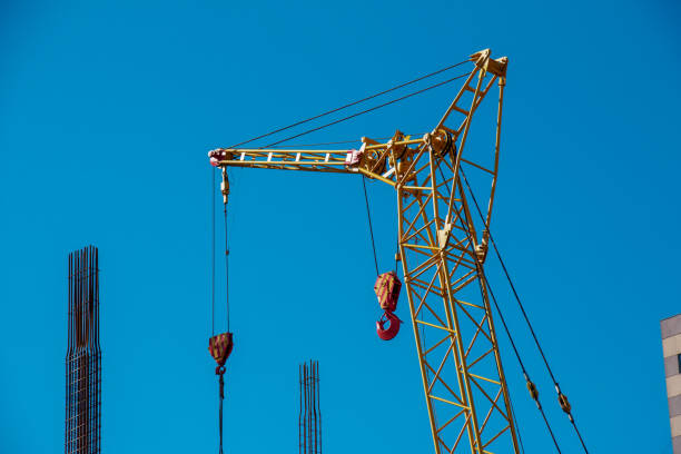 High-rise construction crane with a long yellow boom against the blue sky. stock photo