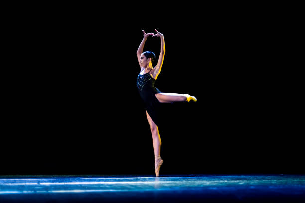 young girl performing neo-classic ballet wearing a black dress on a dark stage - round bale imagens e fotografias de stock