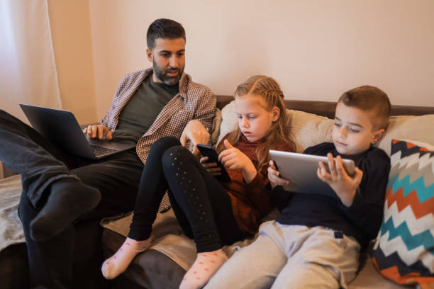 istock Father and his two young children using devices at home 1392010570