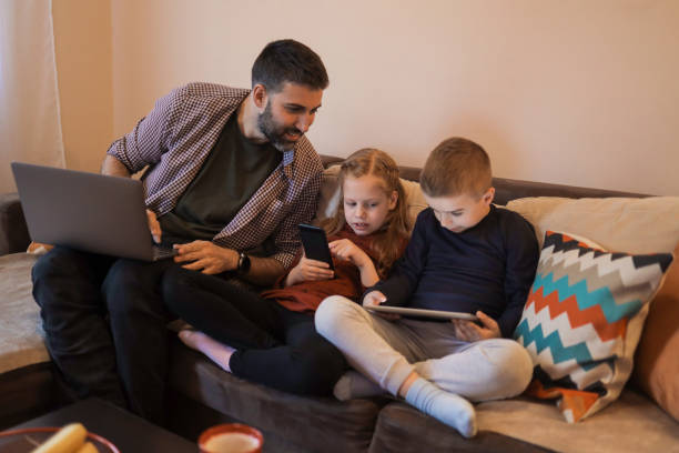 istock Father and his two young children using devices at home 1392010756
