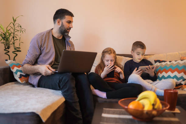 istock Father and his two young children using devices at home 1392010833