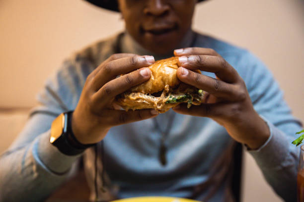 istock Young African American man enjoying eating burger and drinking cocktail 1392014855