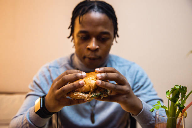 istock Young African American man enjoying eating burger and drinking cocktail 1392014873