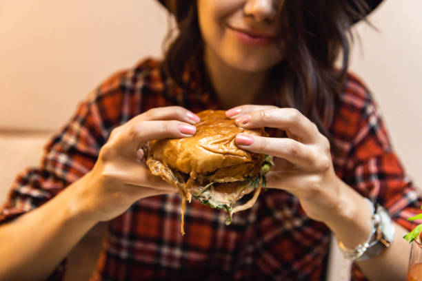 istock Young woman enjoying eating burger and drinking cocktail 1392014887