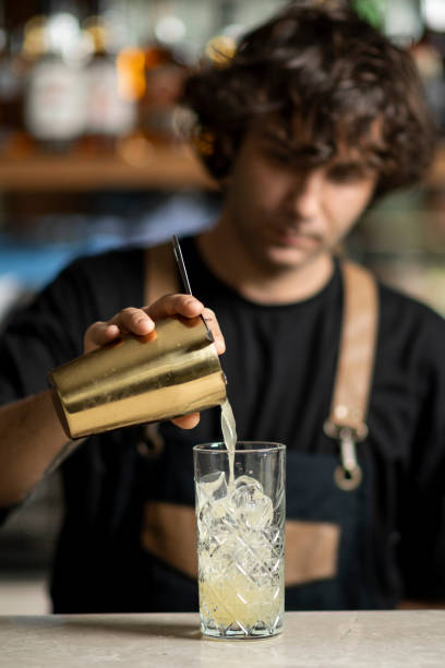Bartender preparing tasty cocktail, using cocktail shaker stock photo