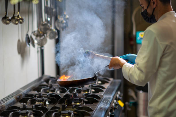 Chef preparing food over a flaming gas stove stock photo