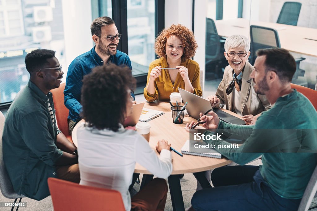 Mixed group of business people sitting around a table and talking Multiracial group of business people having a meeting Teamwork Stock Photo