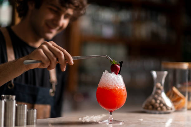 Bartender adding a strawberry to an icy cocktail stock photo