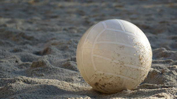 Beach volleyball sitting in the sand in the morning light