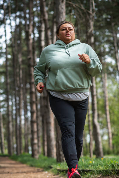 istock Overweight Hispanic woman sweating and exhausted running in a forest 1392029053