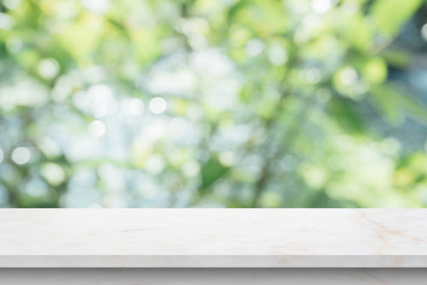 istock Marble table top with blur green leaf bokeh nature background 1392030665