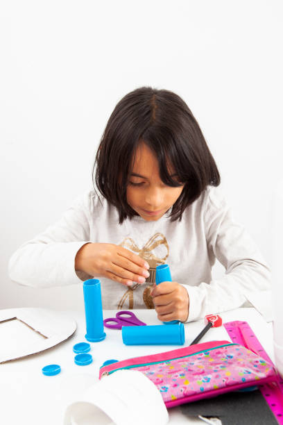 istock Young girl making a toy microscope with recyclable material 1392036576