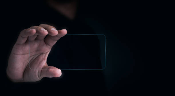 istock Future transparent glass phone Technology. Mock-up blank screen futuristic transparent smartphone in human hand on dark with copy space, horizontal. Future technology communication equipment. 1392046948