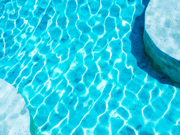 istock Clean and clear blue water surface with movement wave shining with the light on the curved shape swimming pool background. Summer background, vacation time, holiday concept. 1392047141