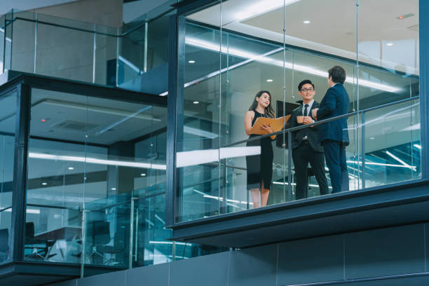 esterno dell'edificio dell'ufficio che guarda attraverso la finestra incontro cinese dell'uomo d'affari che lavora a tarda notte nella sala riunioni - business buildings foto e immagini stock