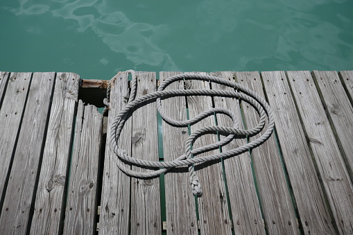 Old wooden boat dock with rope by ocean water