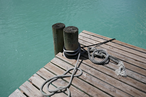 Wooden mooring bollard and dock with ropes by ocean