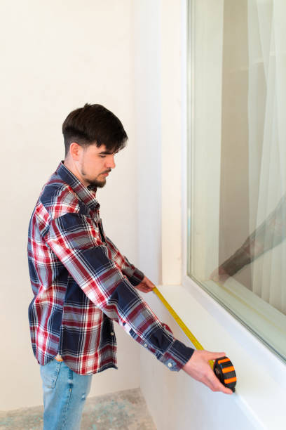istock builder-repairer measures the length of the installed window sill 1392059688