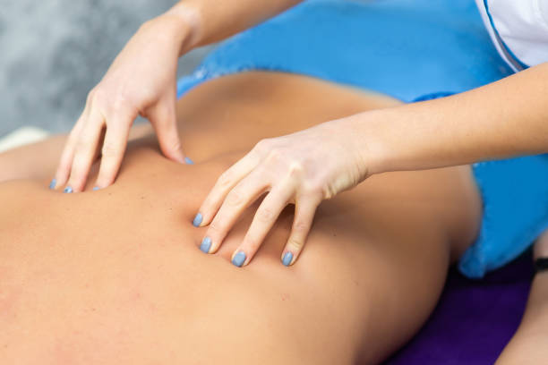 istock woman masseur doing back massage to client man on massage table, closeup 1392060812