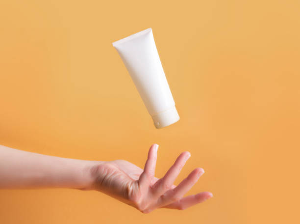 istock Woman's hand with cream on orange background with palm up 1392061464