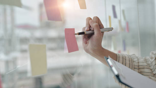 istock Businessman writing new idea on sticky notes at bright modern office. 1392069403
