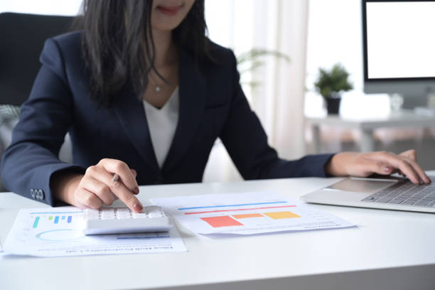 istock Professional investor using calculator and checking financial reports at her workplace. 1392069464
