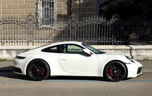 Udine, Italy. April 16, 2022. White Porsche 911Carrera 4s parked in a city street. Side view.