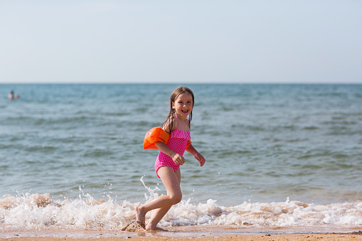 happy child runs along beach on sea. kids fun in summer