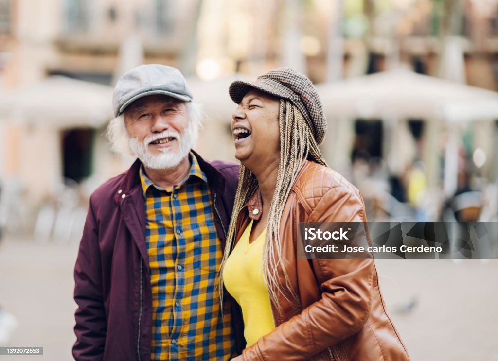 multiracial senior couple having fun in the city, retired travellers' life - focus on women - Multiracial Group Stock Photo