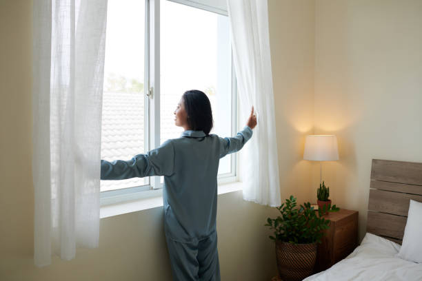 istock Smiling Woman Opening Curtains 1392072754