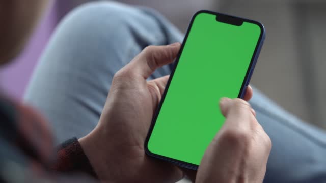 Man Using Smartphone in Vertical Mode with Green Mock-up Screen, Doing Swiping, Scrolling Gestures. Internet Social Networks Browsing News, Financial Reports