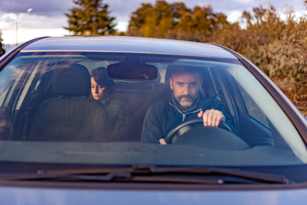 istock Driver with rear passenger drives with care in natural environment at sunset. View from the outside of the front windshield 1392073848